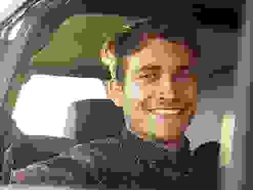 Portrait of a smiling young man looking out through his driver's side window